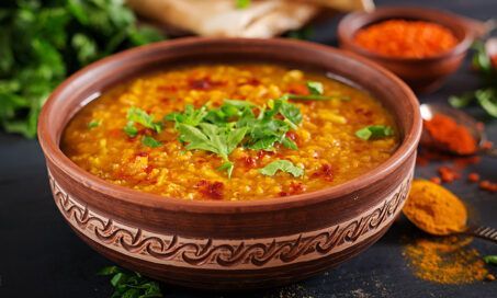 Indian Dhal spicy curry in bowl, spices, herbs, on a wooden bowl.
